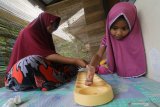 Seorang anak bermain dakon bersama orang tuanya di Kota Kediri, Jawa Timur, Kamis (2/4/2020). Permainan tradisional tersebut dikenalkan oleh orang tua agar anak tidak bosan berada di rumah sebagai upaya mematuhi anjuran pemerintah untuk tidak bermain di tempat publik guna mencegah penyebaran COVID-19. Antara Jatim/Prasetia Fauzani/zk.