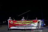 Petugas Kepolisian membentangkan spanduk imbauan di perbatasan Kabupaten Bone Bolango dan Kota Gorontalo di Kabila, Kabupaten Bone Bolango, Gorontalo, Jumat (03/04/2020) malam. Polres Bone Bolango memberikan sosialisasi dan imbauan serta mengalihkan sejumlah kendaraan agar masyarakat tetap berada di rumah guna mencegah penyebaran pandemi virus corona baru atau COVID-19 agar wilayah itu tidak ada yang terjangkit. (ANTARA FOTO/Adiwinata Solihin)