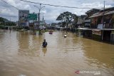 Warga berjalan melintasi banjir di Jalan Raya Dayeuhkolot, Kabupaten Bandung, Jawa Barat, Minggu (5/4/2020). Sedikitnya 104 ribu warga dari 13 kecamatan di kawasan Bandung Selatan terdampak banjir akibat luapan Sungai Citarum dan intensitas curah hujan yang tinggi. ANTARA JABAR/Novrian Arbi/agr