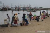 Warga dan nelayan bertransaksi ikan di Pantai Jumiang, Pamekasan, Jawa Timur, Minggu (5/4/2020). Dalam beberapa hari terakhir warga di daerah itu lebih memilih membeli ikan langsung ke nelayan dibanding ke pasar, pasca mewabahnya COVID-19. Antara Jatim/Saiful Bahri/zk