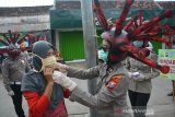 Anggota polisi lalu lintas Polres Mojokerto membagikan masker saat sosialisasi penggunaan masker dengan memakai helm virus COVID-19 di pasar tradisional Sawahan, Kecamatan Bangsal, Kabupaten Mojokerto, Jawa Timur, Rabu (8/4/2020). Polres Mojokerto memakai cara unik untuk menyadarkan masyarakat terkait kewajiban menggunakan masker saat keluar rumah agar terhindar dari virus COVID-19. Selain itu mereka juga membagikan masker gratis kepada para pedagang serta masyarakat yang ada di sekitar pasar. Antara Jatim/Syaiful Arif/zk.