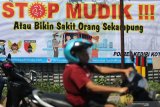 Warga melintas di depan spanduk bertuliskan 'stop mudik' di Kota Kediri, Jawa Timur, Rabu (8/4/2020). Polresta Kediri menghimbau masyarakat untuk tidak mudik guna menghindari penyebaran COVID-19. Antara Jatim/Prasetia Fauzani/zk.