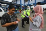 Petugas kepolisian Satuan lalu lintas (Satlantas) Polresta Banjarmasin memberikan masker gratis kepada warga di Terminal Angkutan Umum Pal 6, Banjarmasin, Kalimantan Selatan, Rabu (8/4/2020). Satlantas Polresta Banjarmasin bersama BPBD Kota Banjarmasin dan Dinas Kesehatan Kota Banjarmasin melakukan penyemprotan disinfektan dan sosialisasi pencegahan penyebaran virus COVID-19 serta membagikan masker secara gratis kepada warga di kawasan Terminal Angkutan Umum Pal 6 Banjarmasin. Foto Antaranews Kalsel/Bayu Pratama S.