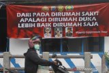 Pengendara melintas di dekat spanduk himbauan untuk tetap dirumah di jalan Veteran, Banjarmasin, Kalimantan Selatan, Rabu (8/4/2020). Pemerintah bersama unsur pimpinan daerah terus berupaya mengajak serta menghimbau masyarakat untuk melalukan pencegahan penyebaran virus COVID-19, salah satunya dengan mematuhi imbauan yang dikeluarkan pemerintah dalam penanganan wabah COVID-19. Foto Antaranews Kalsel/Bayu Pratama S.