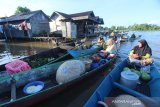 Pedagang menjajakan dagangannya di atas perahu di pasar terapung Lok Baintan, Desa Lok Baintan, Kabupaten Banjar, Kalimantan Selatan, Jumat (10/4/2020). Menurut pedagang setempat, pembeli maupun wisatawan yang berkunjung ke pasar tersebut mengalami penurunan sejak merebaknya wabah COVID-19. Foto Antaranews Kalsel/Bayu Pratama S.