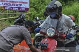 Petugas menempelkan stiker pada kendaraan bermotor seusai pemeriksaan di Perbatasan Tasikmalaya-Ciamis, Jembatan Cirahong, Kabupaten Ciamis, Jawa Barat, Jumat (10/4/2020). Pemkab Ciamis memberlakukan karantina lokal terbatas dengan mendirikan  sembilan Posko percepatan penanganan COVID-19 di wilayah perbatasan. ANTARA JABAR/Adeng Bustomi/agr