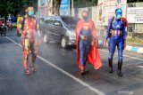 Petugas kepolisian dari polres Pasuruan Kota berpakaian superhero menyemprotkan cairan disinfektan di jalan Panglima Sudirman kawasan Kebonagung, Pasuruan , Jawa Timur, Kamis (9/4/2020). Penyemprotan cairan disinfektan tersebut bertujuan untuk mengantisipasi penyebaran Virus Corona (COVID-19). Antara Jatim/Umarul Faruq/zk