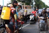 Kapolres Pasuruan Kota AKBP Dony Alexander (kedua kiri) memberikan masker pengendara saat superhero menyemprotkan cairan disinfektan di jalan Panglima Sudirman kawasan Kebonagung, Pasuruan , Jawa Timur, Kamis (9/4/2020). Pembagian masker dan penyemprotan cairan disinfektan tersebut bertujuan untuk mengantisipasi penyebaran Virus Corona (COVID-19). Antara Jatim/Umarul Faruq/zk