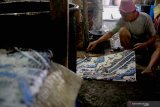 Perajin menyelesaikan polesan terakhir produk batik tulis di UMKM Batik Gajah Mada di Mojosari, Tulungagung, Jawa Timur, Kamis (9/4/2020). Pandemi wabah COVID-19 yang terjadi di sebagian besar wilayah di Indonesia beberapa pekan terakhir telah menyebabkan mayoritas UMKM batik di daerah itu terpaksa menghentikan produksi akibat minimnya permintaan pelanggan, terutama dari sektor korporat/bisnis yang biasanya memiliki pesanan dengan omzet besar. Antara Jatim/Destyan Sujarwoko/zk