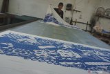Perajin menyelesaikan proses pengeringan produk batik dengan teknik sablon yang tersisa di UMKM Batik Gajah Mada di Mojosari, Tulungagung, Jawa Timur, Kamis (9/4/2020). Pandemi wabah COVID-19 yang terjadi di sebagian besar wilayah di Indonesia beberapa pekan terakhir telah menyebabkan mayoritas UMKM batik di daerah itu terpaksa menghentikan produksi akibat minimnya permintaan pelanggan, terutama dari sektor korporat/bisnis yang biasanya memiliki pesanan dengan omzet besar. Antara Jatim/Destyan Sujarwoko/zk