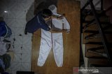 Pekerja mengukur alat pelindung diri (APD) saat produksi di Antapani, Bandung, Jawa Barat, Minggu (12/4/2020). Beberapa pelaku usaha konveksi di Kota Bandung beralih produksi dari kaos distro menjadi APD akibat minimnya permintaan kaos distro dampak dari mewabahnya COVID-19 di Indonesia. ANTARA JABAR/Raisan Al Farisi/agr