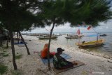 Nelayan penyedia jasa perahu wisata menunggu wisatawan di Pantai Kenjeran, Surabaya, Jawa Timur, Minggu (12/4/2020). Para nelayan di daerah tersebut mengaku pendapatan mereka turun drastis akibat sulitnya menjual hasil tangkapan ikan dan sepinya kunjungan wisatawan untuk menyewa jasa perahu wisata akibat COVID-19. Antara Jatim/Moch Asim/zk.