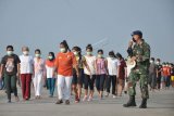 Sejumlah Tenaga Kerja Indonesia (TKI) asal Malaysia mengikuti senam dan berjemur di bawah sinar matahari saat menjalani karantina di Pangkalan Udara Militer (Lanud) Soewondo Medan, Sumatera Utara, Sabtu (11/4/2020). Sebanyak 513 TKI yang berasal dari berbagai daerah di Sumut dan sekitarnya yang menjalani proses karantina COVID-19 sementara tersebut saat ini kondisi kesehatannya baik dan tidak ada menunjukan gejala infeksi seperti demam, batuk dan sesak nafas. ANTARA FOTO/Septianda Perdana/hp.