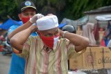 Petugas Badan Narkotika Nasional Provinsi (BNNP) Aceh membantu memasangkan masker merah putih kepada pedagang di Pasar Tradisional Peunanyung, Banda Aceh, Aceh, Selasa (14/4/2020). Pembagian masker gratis yang disertai sosialisasi kepada pedagang dan pengunjung di pusat pasar tradisional itu untuk mencegah penyebaran COVID-19. Antara Aceh/Ampelsa.