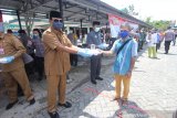 Gubernur Kalimantan Selatan Sahbirin Noor (kiri) memberikan makanan gratis kepada warga di halaman Masjid Jami, Banjarmasin, Kalimantan Selatan, Selasa (14/4/2020). Polda Kalimantan Selatan bersama TNI dan Pemerintah Provinsi Kalsel membagikan makanan gratis dan masker sebagai bentuk kepedulian terhadap warga terdampak COVID-19 di Kota Banjarmasin. Foto Antaranews Kalsel/Bayu Pratama S.