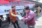 Wakil Ketua DPRD Provinsi Kalsel M Syaripuddin (kiri) memberikan makanan gratis kepada warga di halaman Masjid Jami, Banjarmasin, Kalimantan Selatan, Selasa (14/4/2020). Polda Kalimantan Selatan bersama TNI dan Pemerintah Provinsi Kalsel membagikan makanan gratis dan masker sebagai bentuk kepedulian terhadap warga terdampak COVID-19 di Kota Banjarmasin. Foto Antaranews Kalsel/Bayu Pratama S.