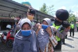 Anggota Polisi memasangkan masker kepada warga saat antre untuk mendapatkan makanan gratis di halaman Masjid Jami, Banjarmasin, Kalimantan Selatan, Selasa (14/4/2020). Polda Kalimantan Selatan bersama TNI dan Pemerintah Provinsi Kalsel membagikan makanan gratis dan masker sebagai bentuk kepedulian terhadap warga terdampak COVID-19 di Kota Banjarmasin. Foto Antaranews Kalsel/Bayu Pratama S.