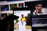 Warga mengamati akun instagram anak angkat bintang sepakbola Juventus Cristiano Ronaldo, Martunis di Kota Kediri, Jawa Timur, Kamis (16/4/2020). Penyitas tragedi tsunami Aceh 2004 tersebut melelang jersey pemberian ayah angkatnya melaui instagram untuk menangani pandemi COVID-19. Antara Jatim/Prasetia Fauzani/zk.