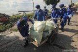 Polisi membawa beras untuk dibagikan kepada nelayan saat bakti sosial di kawasan Cumpat Kulon, Surabaya, Jawa Timur, Jumat (17/4/2020). Bakti sosial dengan pemberian bantuan sembako dan masker oleh Ditpolairud Polda Jawa Timur itu untuk meringankan beban ekonomi nelayan dan masyarakat pesisir di tengah wabah COVID-19. Antara Jatim/Didik/Zk