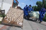 Polisi membawa beras untuk dibagikan kepada nelayan saat bakti sosial di kawasan Cumpat Kulon, Surabaya, Jawa Timur, Jumat (17/4/2020). Bakti sosial dengan pemberian bantuan sembako dan masker oleh Ditpolairud Polda Jawa Timur itu untuk meringankan beban ekonomi nelayan dan masyarakat pesisir di tengah wabah COVID-19. Antara Jatim/Didik/Zk