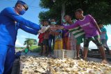 Polisi membagikan masker kepada sejumlah anak saat bakti sosial di kawasan Cumpat Kulon, Surabaya, Jawa Timur, Jumat (17/4/2020). Bakti sosial dengan pemberian bantuan sembako dan masker oleh Ditpolairud Polda Jawa Timur itu untuk meringankan beban ekonomi nelayan dan masyarakat pesisir di tengah wabah COVID-19. Antara Jatim/Didik/Zk