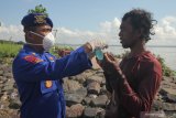 Polisi membagikan masker kepada nelayan saat bakti sosial di kawasan Cumpat Kulon, Surabaya, Jawa Timur, Jumat (17/4/2020). Bakti sosial dengan pemberian bantuan sembako dan masker oleh Ditpolairud Polda Jawa Timur itu untuk meringankan beban ekonomi nelayan dan masyarakat pesisir di tengah wabah COVID-19. Antara Jatim/Didik/Zk