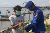 Polisi memberi beras kepada nelayan saat bakti sosial di kawasan Cumpat Kulon, Surabaya, Jawa Timur, Jumat (17/4/2020). Bakti sosial dengan pemberian bantuan sembako dan masker oleh Ditpolairud Polda Jawa Timur itu untuk meringankan beban ekonomi nelayan dan masyarakat pesisir di tengah wabah COVID-19. Antara Jatim/Didik/Zk