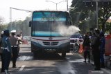 Polisi berpakaian tokoh wayang menyemprotkan larutan disinfektan ke kendaraan bermotor yang memasuki Surabaya di pintu keluar Jembatan Suramadu, Surabaya, Jawa Timur, Senin (20/4/2020). Kegiatan itu untuk menghambat dan memutus penyebaran Covid-19. Antara Jatim/Didik/Zk