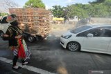 Polisi berpakaian tokoh wayang menyemprotkan larutan disinfektan ke kendaraan bermotor yang memasuki Surabaya di pintu keluar Jembatan Suramadu, Surabaya, Jawa Timur, Senin (20/4/2020). Kegiatan itu untuk menghambat dan memutus penyebaran Covid-19. Antara Jatim/Didik/Zk