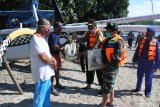 Dandim 0823 Situbondo Letkol Inf Akhmad Juni Toa (kedua kanan), Kapolres Situbondo AKBP Sugandi (ketiga kanan), memberikan paket sembako ke nelayan perahu layar di objek Wisata Bahari Pasir Putih, Bungatan, Situbondo, Jawa Timur, Selasa (21/4/2020). Polres Situbondo membagikan paket sembako yang berisi beras, gula, minyak goreng kepada nelayan, pelaku usaha kecil menengah terdampak wabah COVID-19 karena pendapatan mereka hilang atau berkurang. Antara Jatim/Seno/zk.