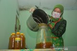 Ummi Fitria, menyelesaikan pembuatan minuman kunyit asam di Kelurahan Jombatan, Kabupaten Jombang, Jawa Timur, Rabu (22/4/2020). Industri rumahan minuman kemasan kunyit asam tersebut tidak terdampak pandemi virus Corona, dalam sehari mereka bisa memproduksi 300-400 botol dibandingkan sebelumnya hanya 100-200 botol per harinya, karena minuman ini dianggap bisa meningkatkan daya tahan tubuh. Antara Jatim/Syaiful Arif/zk.