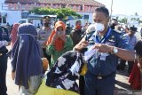 Petugas Kantor Kesyahbandaran dan Otoritas Pelabuhan (KSOP) Kelas IV Panarukan memberikan masker ke calon penumpang kapal motor di area Pelabuhan Kalbut, Mangaran, Situbondo, Jawa Timur, Rabu (22/4/2020). Sejumlah warga Pulau Sapudi, Sumenep yang bekerja di Bali pulang kampung lebih awal meski Pemerintah resmi melarang pelaksanaan mudik Lebaran 2020 guna mencegah penyebaran COVID-19. Antara Jatim/Seno/zk.