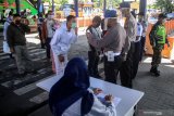 Sejumlah petugas memeriksa Kartu Tanda Pengenal penumpang saat tiba di kedatangan Terminal Bungurasih, Sidoarjo, Jawa Timur, Kamis (23/4/2020). Pemerintah Indonesia resmi mengeluarkan kebijakan larangan mudik Lebaran 2020 bagi masyarakat di tengah masa Pandemi guna memutus mata rantai penyebaran virus corona atau COVID-19 yang akan berlaku ekfektif mulai Jumat 24 April 2020. Antara Jatim/Umarul Faruq/zk