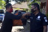 Petugas melakukan salam siku dengan narapidana yang menerima bantuan di Balai Pemasyarakatan Kelas I Denpasar, Bali, Kamis (23/4/2020). Balai Pemasyarakatan Kelas I Denpasar memperingati Hari Bakti Pemasyarakatan ke-56 dengan menyerahkan bantuan berupa sembako, masker, hand sanitizer dan alat mandi kepada 20 orang narapidana kurang mampu yang menerima program asimilasi dan integrasi dalam rangka pencegahan penyebaran COVID-19. ANTARA FOTO/Fikri Yusuf/nym.