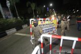 Petugas memasang pagar untuk menutup jalan masuk dalam kota saat pemberlakuan jam malam di perbatasan Kota Banjarmasin, Kalimantan Selatan, Jumat (24/4/2020) malam. Saat pemberlakuan jam malam untuk mendukung Pembatasan Sosial Berskala Besar (PSBB) di Kota Banjarmasin, jalan masuk menuju dalam kota di tutup namun boleh masuk dengan akses terbatas melalui pemeriksaan oleh petugas guna mencegah penyebaran COVID-19. Foto Antaranews Kalsel/Bayu Pratama S.