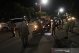 Petugas memeriksa pengguna jalan yang akan masuk kedalam Kota di perbatasan Kota Banjarmasin, Kalimantan Selatan, Jumat (24/4/2020) malam. Saat pemberlakuan jam malam untuk mendukung Pembatasan Sosial Berskala Besar (PSBB) di Kota Banjarmasin, jalan masuk menuju dalam kota di tutup namun boleh masuk dengan akses terbatas melalui pemeriksaan oleh petugas guna mencegah penyebaran COVID-19. Foto Antaranews Kalsel/Bayu Pratama S.