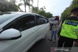 Penumpang mobil berpindah tempat duduk setelah mendapat teguran dari petugas saat Pembatasan Sosial Berskala Besar (PSBB) di perbatasan Kota Banjarmasin, Kalimantan Selatan, Jumat (24/4/2020). Pemerintah Kota Banjarmasin resmi menerapkan PSBB dalam rangka percepatan penangan COVID-19 selama 14 hari dimulai pada 24 April hingga 7 Mei 2020. Foto Antaranews Kalsel/Bayu Pratama S.