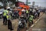 Petugas memberhentikan kendaraan bermotor di titik penyekatan larangan mudik di Jatinangor, perbatasan Kabupaten Bandung dan Kabupaten Sumedang, Jawa Barat, Sabtu (25/4/2020). Penyekatan oleh tim gabungan dari TNI, Polri, Dishub, dan Satpol PP tersebut dilakukan sebagai salah satu langkah penertiban larangan sementara penggunaan transportasi umum, kendaraan pribadi dan sepeda motor untuk mudik. ANTARA JABAR/Raisan Al Farisi/agr