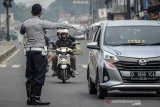 Petugas memberhentikan kendaraan bermotor di titik penyekatan larangan mudik di Jatinangor, perbatasan Kabupaten Bandung dan Kabupaten Sumedang, Jawa Barat, Sabtu (25/4/2020). Penyekatan oleh tim gabungan dari TNI, Polri, Dishub, dan Satpol PP tersebut dilakukan sebagai salah satu langkah penertiban larangan sementara penggunaan transportasi umum, kendaraan pribadi dan sepeda motor untuk mudik. ANTARA JABAR/Raisan Al Farisi/agr