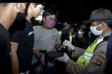 Polisi memeriksa sejumlah remaja yang akan melakukan aksi balap liar saat patroli pencegahan penyebaran COVID-19 di wilayah Jimbaran, Badung, Bali, Minggu (26/4/2020). Patroli yang melibatkan unsur Pecalang, Linmas, TNI, dan Polri tersebut dilakukan untuk menertibkan warga yang masih berkumpul di luar rumah serta aksi balap liar yang masih dilakukan sejumlah remaja selama masa pandemi COVID-19. ANTARA FOTO/Fikri Yusuf/nym.