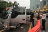 Petugas menghentikan minibus yang mengangkut banyak penumpang yang akan masuk ke Surabaya di Bundaran Waru, Surabaya, Jawa Timur, Selasa (28/4/2020). Petugas gabungan memperketat akses masuk ke Surabaya dengan melakukan screening atau pemeriksaan kepada warga di hari pertama pelaksanaan Pembatasan Sosial Berskala Besar (PSBB) di Surabaya. Antara Jatim/Didik/Zk