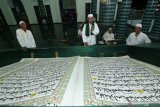 Umat muslim bertadarus membaca Al Quran raksasa di Masjid Baiturrahman, Banyuwangi, Jawa Timur, Senin (27/4/2020). Al Quran raksasa ditulis tangan oleh H Abdul Karim memiliki ukuran halaman 142 x 210 centimeter tersebut, mulai ditulis pada 1 Februari 2010 dan selesai pada 26 Agustus 2010 untuk dibaca setiap bulan Ramadan di Masjid Baiturrahman Banyuwangi Antara Jatim/Budi Candra Setya/zk