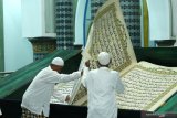 Pengeblat membalik halaman saat bertadarus membaca Al Quran raksasa di Masjid Baiturrahman, Banyuwangi, Jawa Timur, Senin (27/4/2020). Al Quran raksasa ditulis tangan oleh H Abdul Karim memiliki ukuran halaman 142 x 210 centimeter tersebut, mulai ditulis pada 1 Februari 2010 dan selesai pada 26 Agustus 2010 untuk dibaca setiap bulan Ramadan di Masjid Baiturrahman Banyuwangi Antara Jatim/Budi Candra Setya/zk