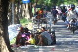 Warga bersantai di dekat gerobak sambil menunggu harapan rezeki di bahu jalan Gatot Subroto, Banjarmasin, Kalimantan Selatan, Jumat (1/5/2020). Saat bulan suci Ramadhan banyak orang bersedekah dengan membagi bagikan makanan kepada kaum duafa, sehingga banyak warga yang kurang mampu menunggu harapan dari orang-orang yang bersedekah. Foto Antaranews Kalsel/Bayu Pratama S.