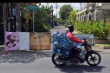 Pengendara motor melintas di dekat jalan perumahahan yang ditutup karena warganya melakukan isolasi mandiri di Denpasar, Bali, Sabtu (2/5/2020). Penutupan jalan tersebut untuk mencegah keluar masuknya orang dalam upaya mengurangi risiko penularan COVID-19. ANTARA FOTO/Nyoman Hendra Wibowo/nym.