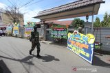 Anggota TNI melintas di dekat karangan bunga ucapan belasungkawa atas wafatnya KH Ahmad Zuhdianoor (Guru Zuhdi) di jalan Masuk Kediaman Guru Zuhdi di Banjarmasin, Kalimantan Selatan, Sabtu (2/5/2020). Guru Zuhdi salah satu ulama Kalimantan Selatan meninggal dunia di Rumah Sakit Medistra Jakarta. Foto Antaranews Kalsel/Bayu Pratama S.