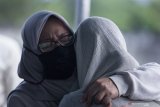 Isteri mendiang musisi Erwin Prasetya, Miranda (kiri) memeluk salah satu putrinya saat proses pemakaman di TPU Keputih, Surabaya, Jawa Timur, Sabtu (2/5/2020).  Mantan gitaris bas grup band Dewa 19 tersebut meninggal dunia pada usia 48 tahun setelah dirawat di rumah sakit Sari Asih Ciputat karena menderita gangguan pada lambungnya. Antara Jatim/Moch Asim/zk.