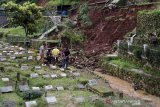 Petugas membersihkan sejumlah makam yang rusak terdampak longsor di TPU Cikutra, Bandung, Jawa Barat, Sabtu (2/5/2020). Material longsor yang berasal dari tebing di kawasan TPU Cikutra tersebut mengakibatkan puluhan makam rusak dan serta sejumlah jenazah sempat terseret arus sungai sebelum dievakuasi oleh petugas pemakaman. ANTARA JABAR/Novrian Arbi/agr