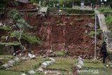 Petugas membersihkan sejumlah makam yang rusak  terdampak longsor di TPU Cikutra, Bandung, Jawa Barat, Sabtu (2/5/2020). Material longsor yang berasal dari tebing di kawasan TPU Cikutra tersebut mengakibatkan puluhan makam rusak dan serta sejumlah jenazah sempat terseret arus sungai sebelum dievakuasi oleh petugas pemakaman. ANTARA JABAR/Novrian Arbi/agr