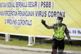 Seorang petugas kepolisian mengatur lalu lintas saat sosialisasi pencanangan Pembatasan Sosial Berskala Besar (PSBB) di Kota Gorontalo, Gorontalo, Senin (4/5/2020). Pemprov Gorontalo melakukan sosialisasi PSBB mulai tanggal 4-6 Mei dan akan diberlakukan secara resmi mulai tanggal 7 Mei 2020 nanti guna memutus mata rantai penyebaran COVID-19. ANTARA FOTO/Adiwinata Solihin